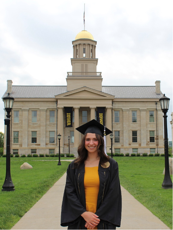 Woman in graduation cap and gown standing outside the Old Capitol